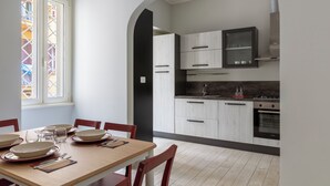 A dining area with a table set for four, a kitchen with modern appliances, and a stained glass window. - Colosseo Road by Hili  (Rome)