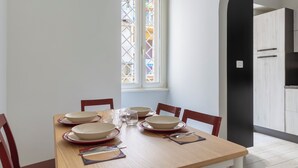 A dining table set with plates, glasses, and cutlery, with a window and cabinets in the background. - Colosseo Road by Hili  (Rome)