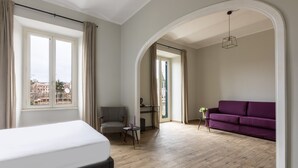 A modern room with a bed, a purple sofa, a small table, and a chair. - Colosseo Road by Hili  (Rome)