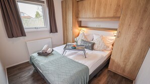 Quarto com cama, mesa de cabeceira e janela.