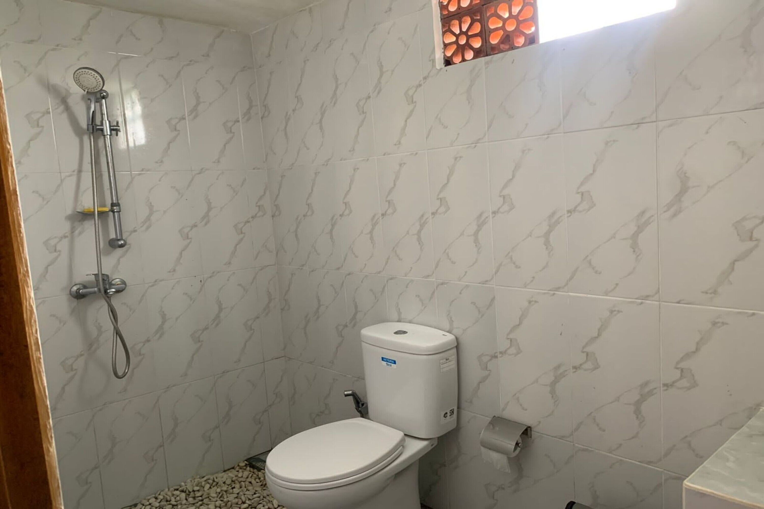 Un baño con inodoro, ducha y pared con diseño de mármol.