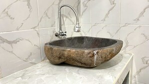 Ein Waschbecken aus Stein mit einem modernen Wasserhahn in einem Badezimmer mit Marmorfliesen.