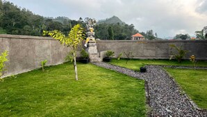 Ein Innenhof mit einer Statue, einem kleinen Baum und einem Weg.