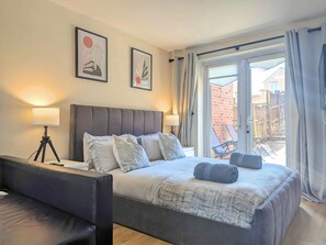 Une chambre moderne avec un grand lit, deux lampes de chevet et une vue sur l’extérieur.