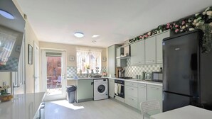 A modern kitchen with a washing machine, a refrigerator, and a dining area. - Spacious 4-bedroom, 3-bath property close to Liverpool city centre, featuring a fully equipped kitchen, bright living room, garden, and free on-street parking. Perfect for families, contractors, or groups seeking comfort and convenience. (Merseyside)