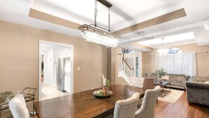 A spacious living room with a large wooden dining table, comfortable seating, and a chandelier. - 4BDR+PrivatePool+Game Room+BBQ+FirePit+Fits12 (Corpus Christi)
