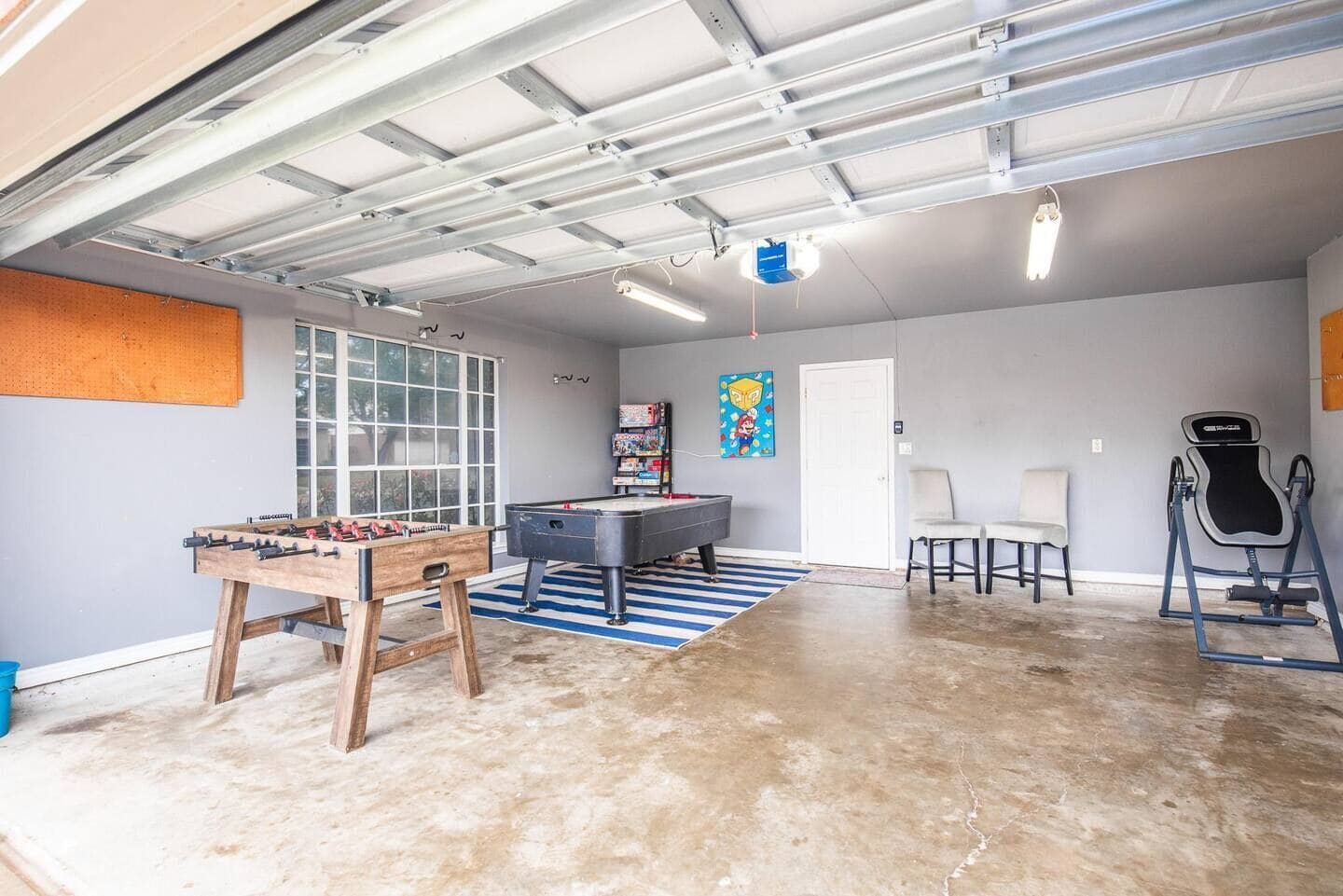 A spacious indoor area with a pool table, foosball table, and exercise equipment.