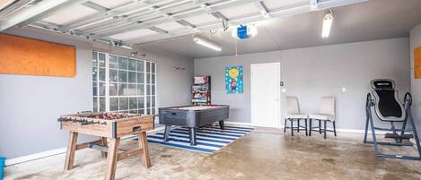 A spacious indoor area with a pool table, foosball table, and exercise equipment.