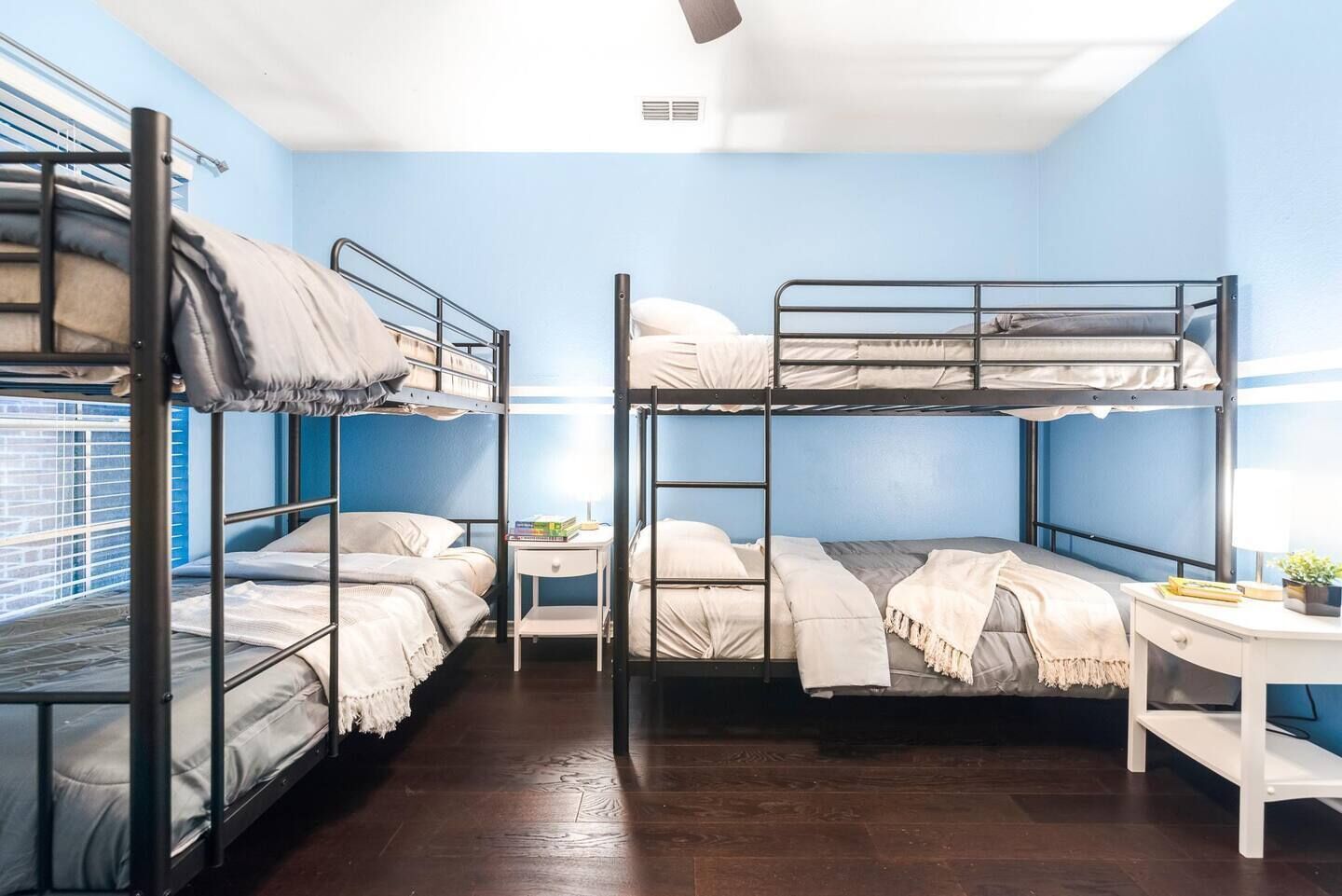 A dormitory room with bunk beds, a desk, and a small bedside table.