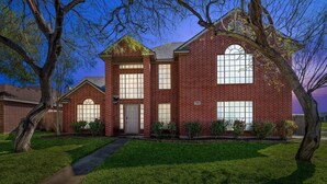 A two-story brick house with a central entrance, large windows, and a well-maintained lawn. - 4BDR+PrivatePool+Game Room+BBQ+FirePit+Fits12 (Corpus Christi)