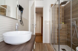 A modern bathroom with a large white sink, a glass shower enclosure, and a wooden floor. - SoClà Boutique Hotel (Taranto)