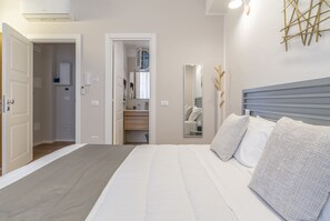 A bedroom with a bed, a bedside table, a mirror, and a wardrobe. - SoClà Boutique Hotel (Taranto)