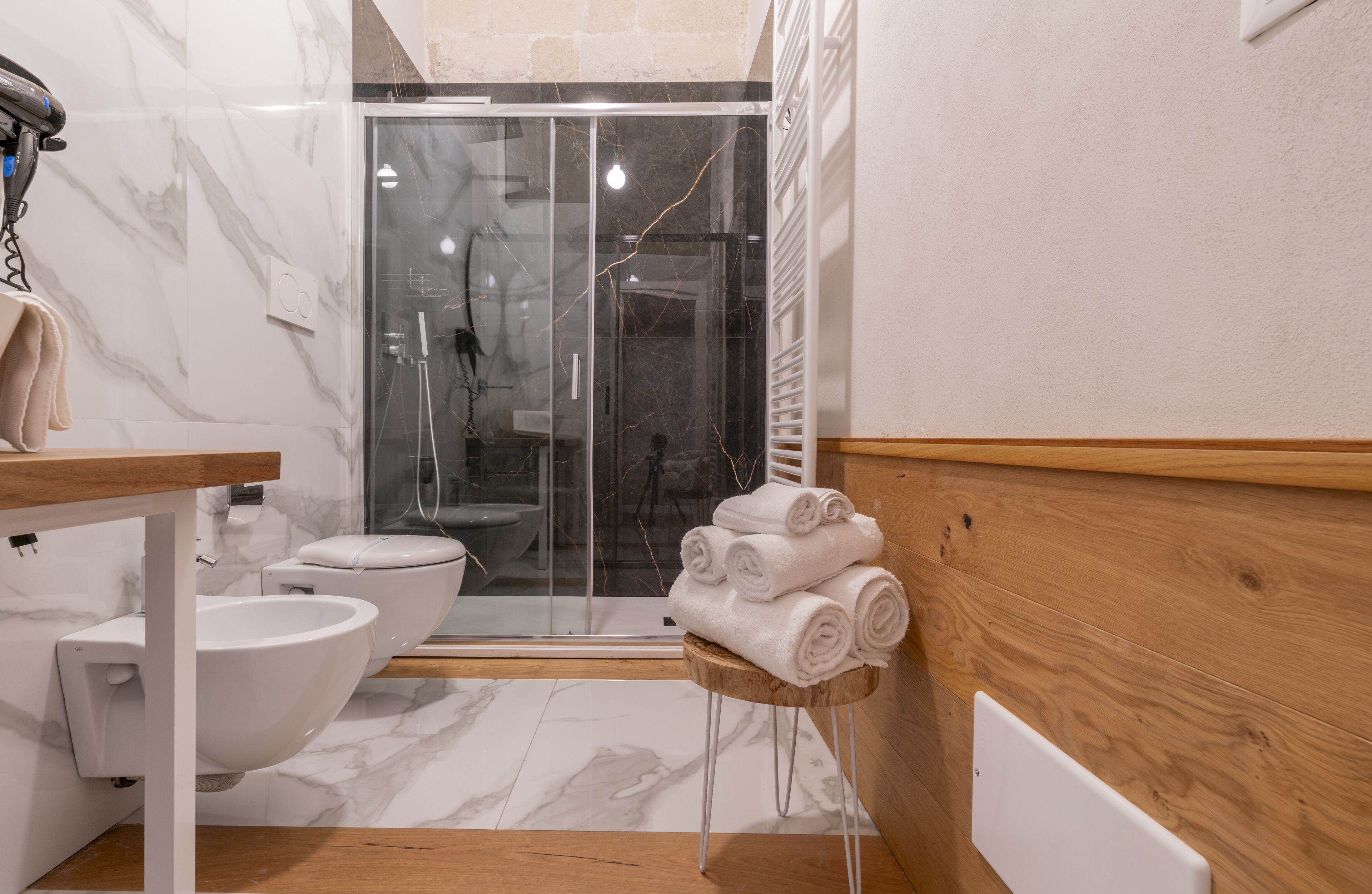 A modern bathroom with a glass shower enclosure, a wooden vanity, a white sink, and a toilet.
