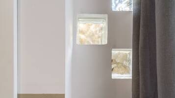 Una habitación con ventana, lámpara de pared y cortina.