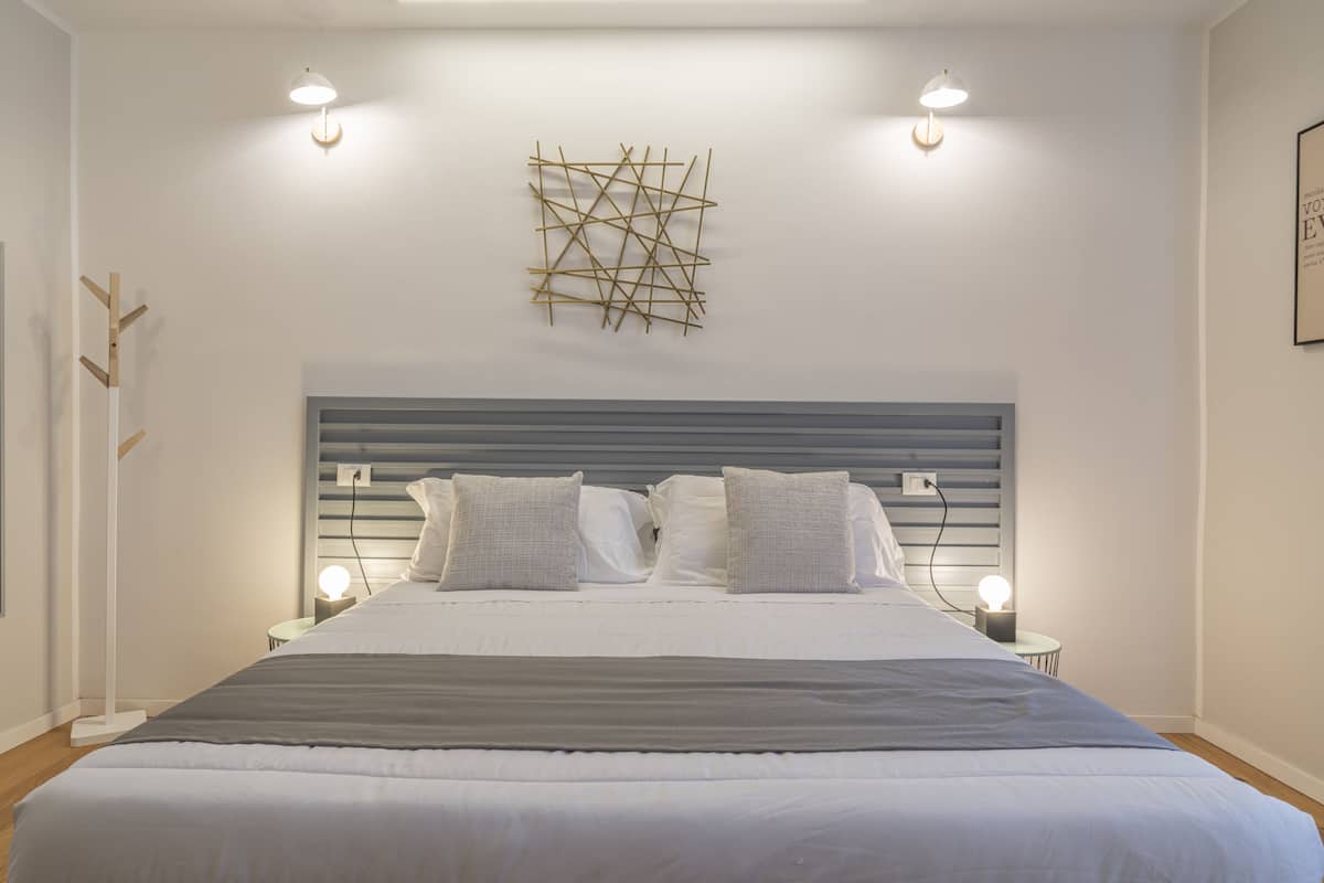 Une chambre moderne avec un grand lit, une tête de lit en bois et deux lampes de chevet.