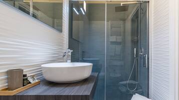 Un baño moderno con un lavamanos grande de color blanco, un mueble de tocador de madera y un box de ducha de vidrio.