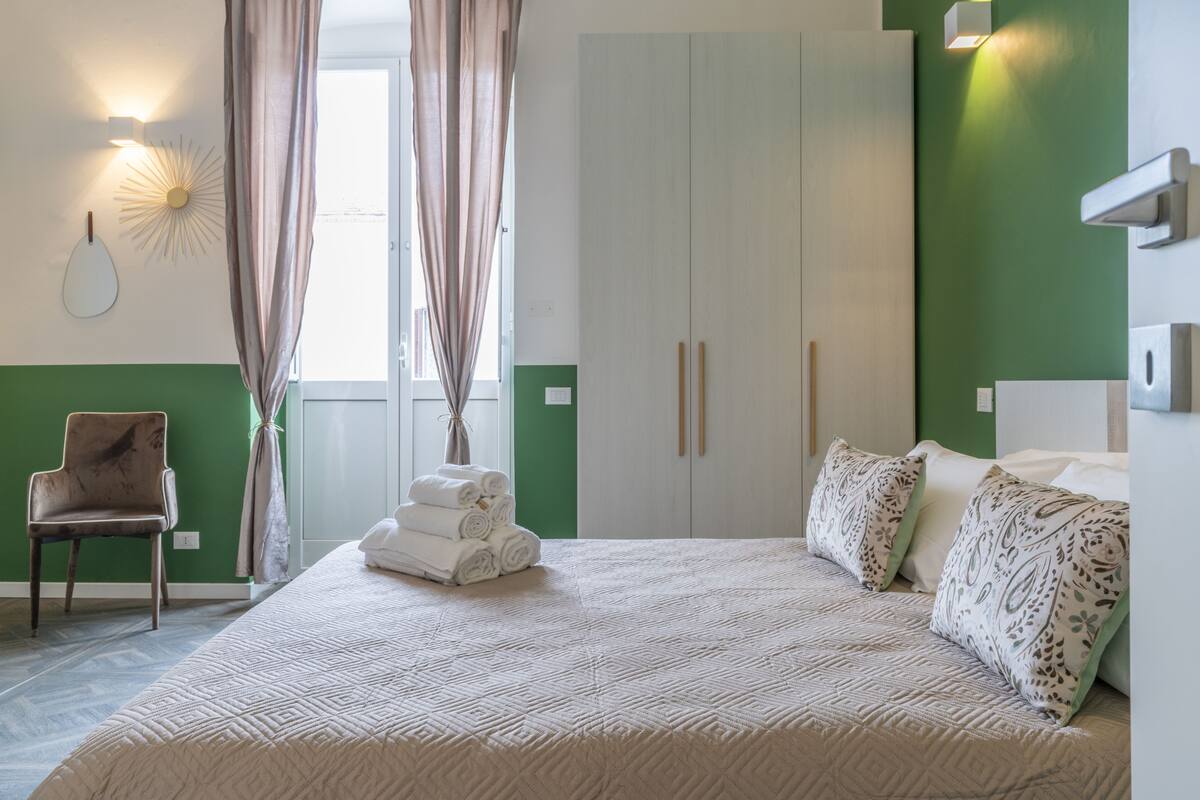 Une chambre à coucher comprenant un lit, une chaise, une armoire et un luminaire fixé au mur.