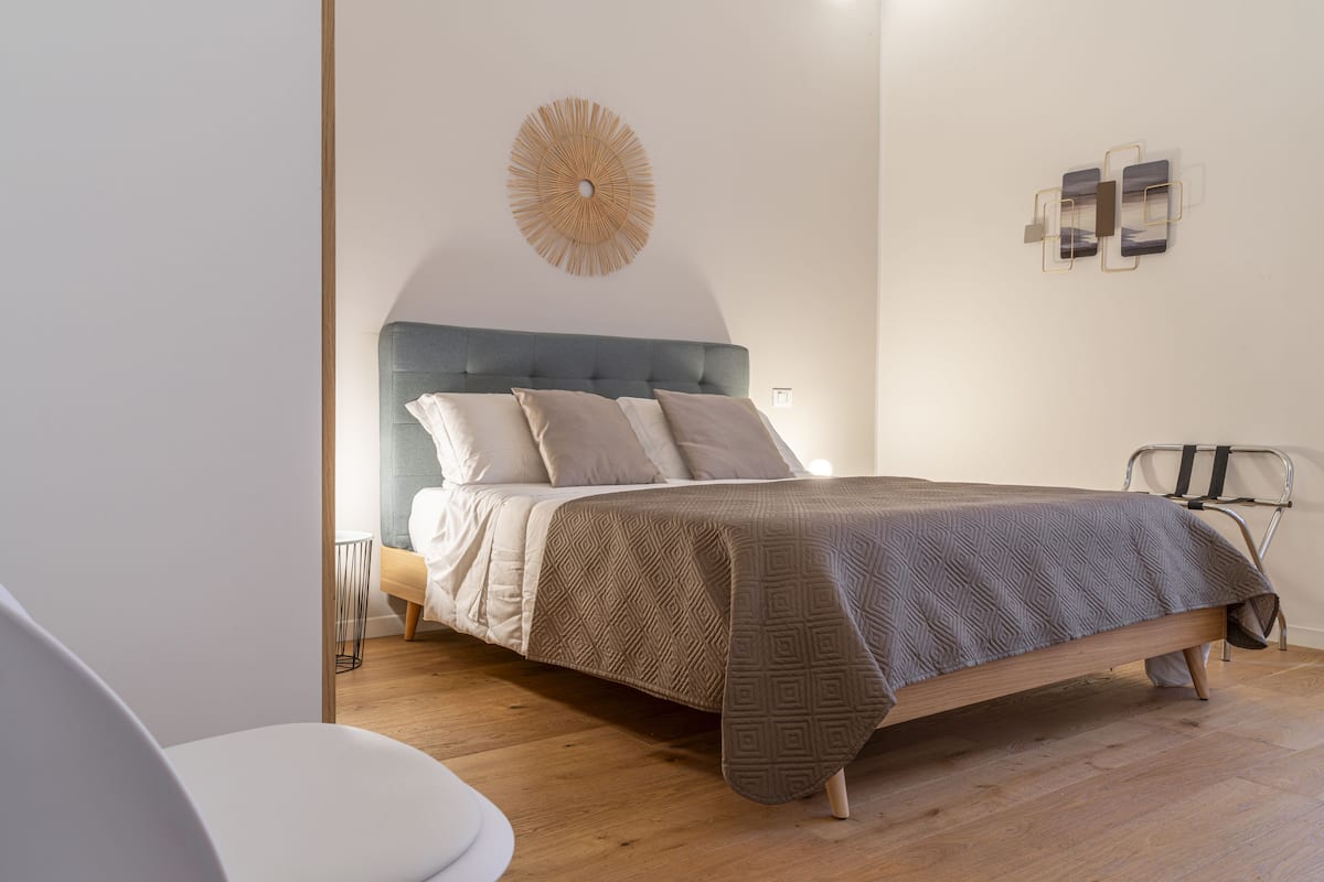 Une chambre à coucher comprenant un lit, une table de chevet, une chaise et un luminaire fixé au mur.