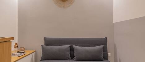 A neatly arranged bedroom with a bed, bedside table, and a wall-mounted decorative item.