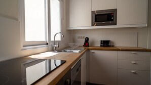 Et lille køkken med vask, mikrobølgeovn og kaffemaskine.