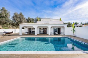 Una casa moderna con piscina, esterno bianco e patio con mobili da giardino.