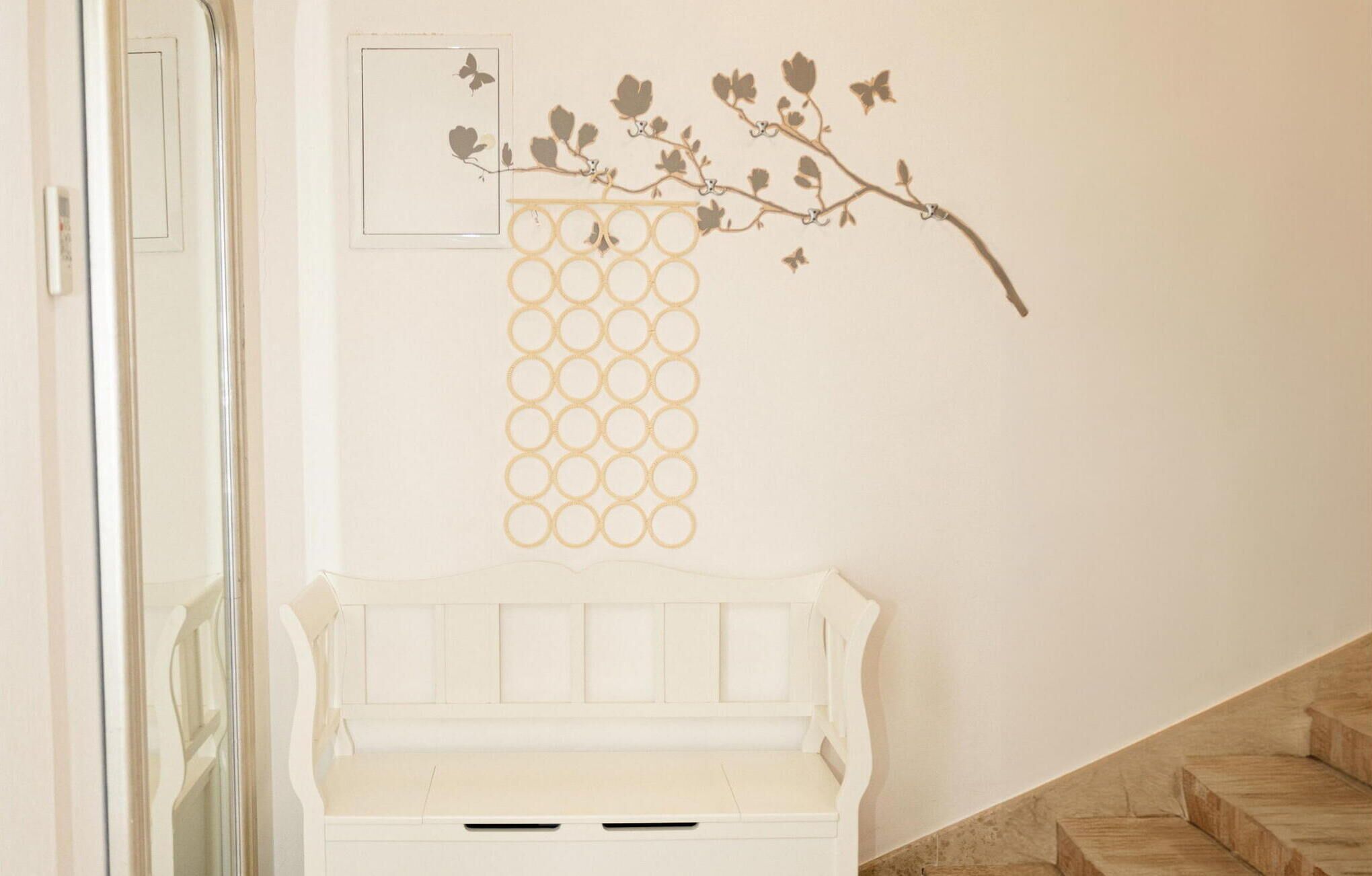 Un banc blanc au design simple, un motif circulaire fixé au mur et un escalier sur le côté droit.