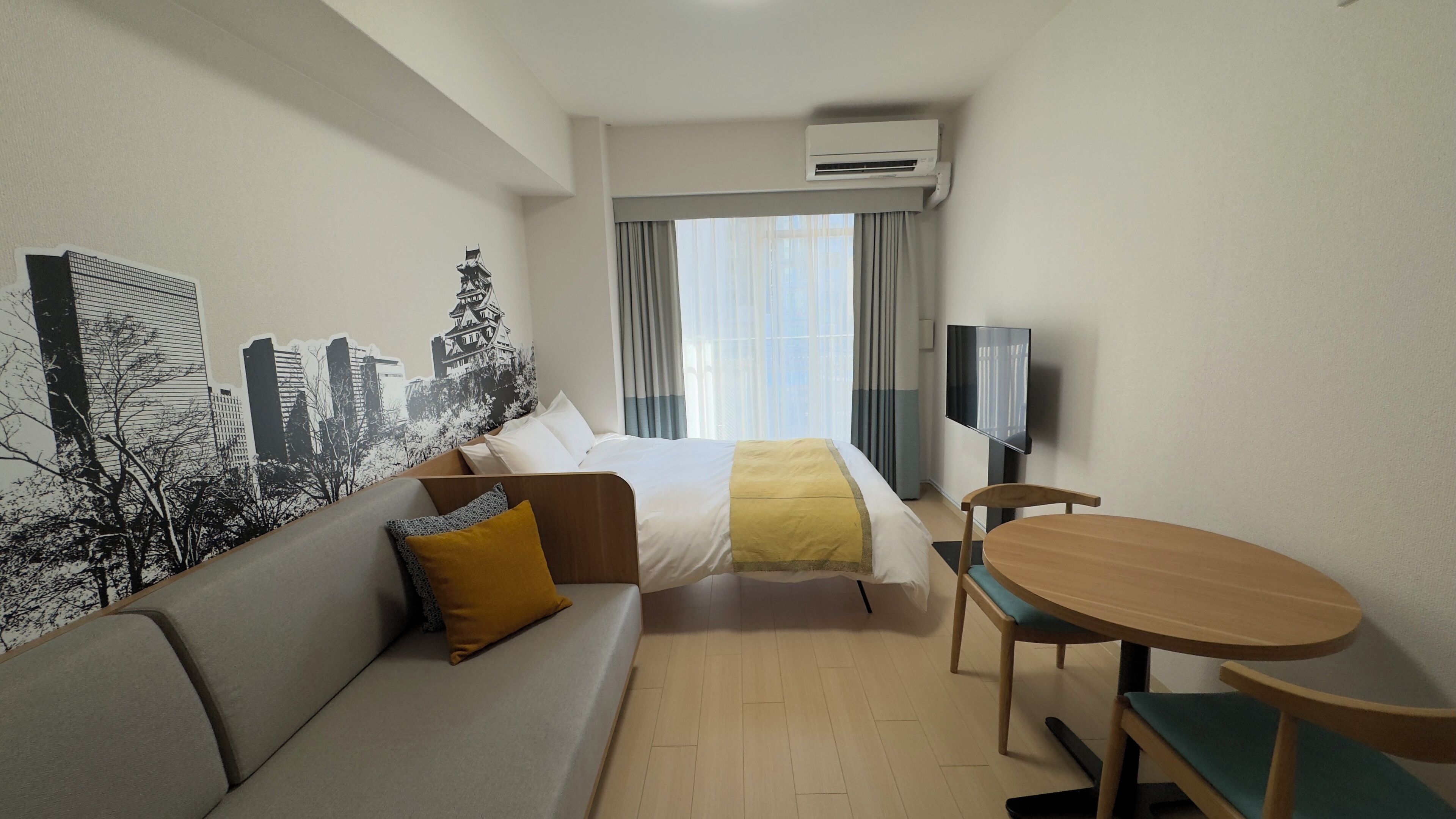 Une chambre d’hôtel équipée d’un lit, d’un canapé, d’une table, d’une télévision et d’un appareil de climatisation.