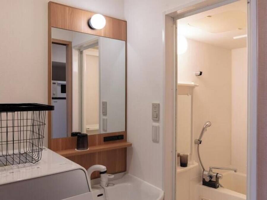 A modern bathroom with a white sink, a mirror, and a shower.