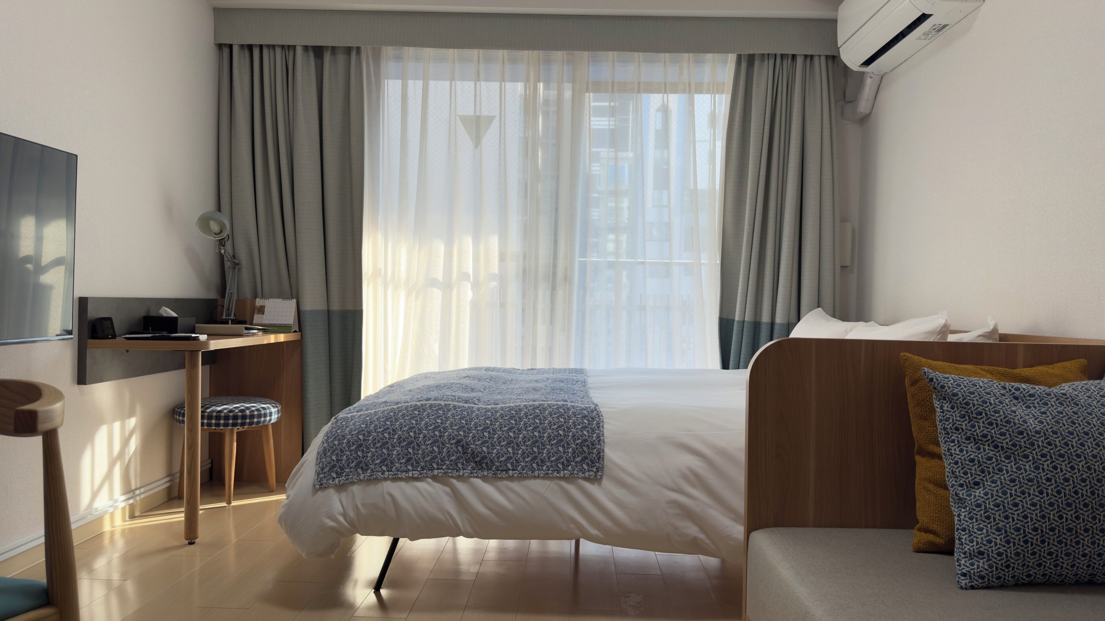 A hotel room with a bed, a desk, a chair, and a couch.
