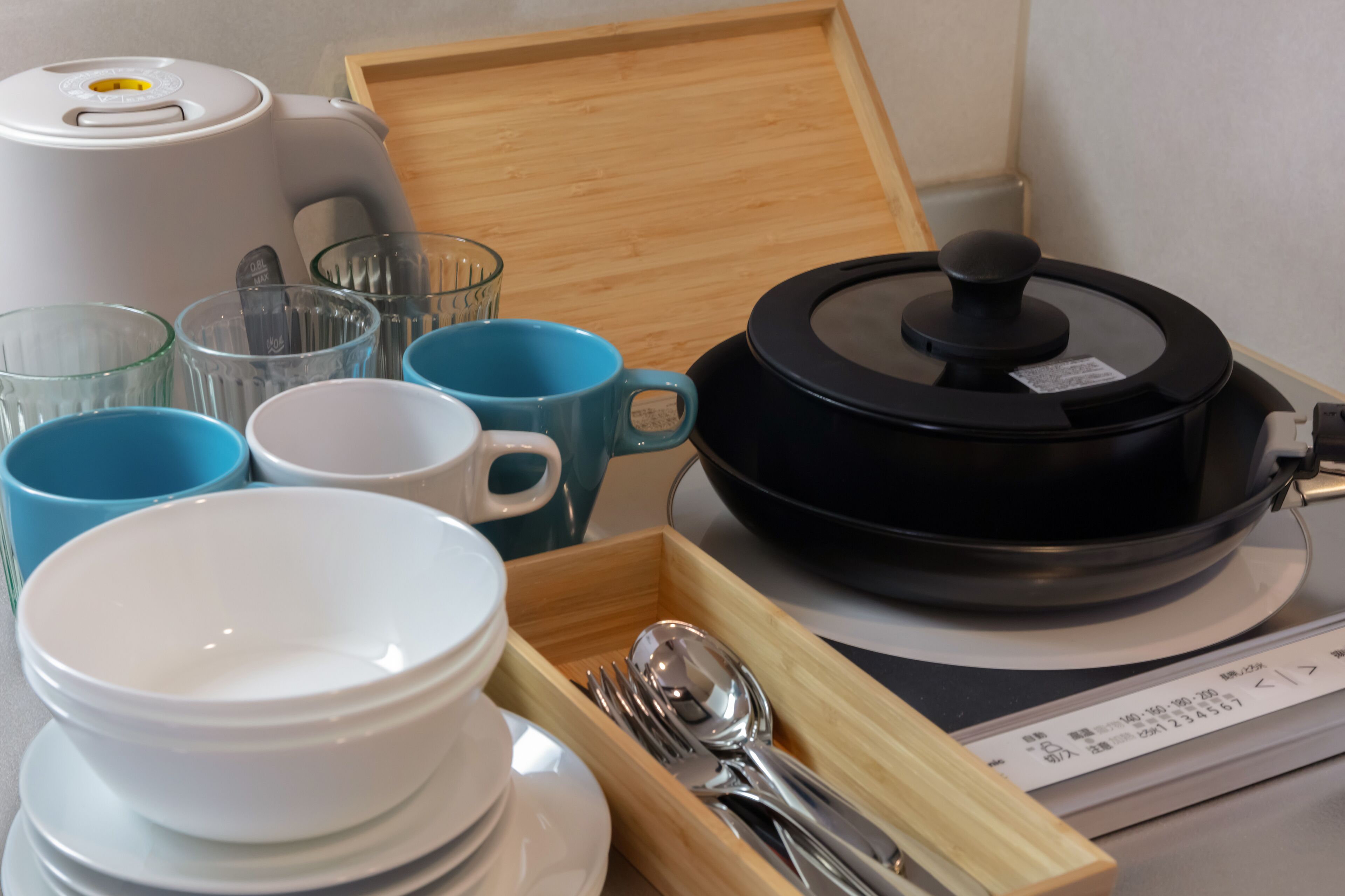 Eine Küchenzeile mit Kaffeemaschine, Reiskocher sowie verschiedenen Schüsseln und Tassen.