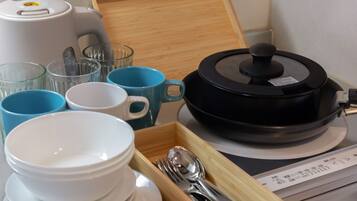 Eine Küchenzeile mit Kaffeemaschine, Reiskocher sowie verschiedenen Schüsseln und Tassen.