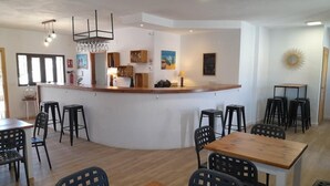 A modern dining area with a central bar, wooden tables, and black chairs. - Condo Entero en Pantano de los Bermejales (Pantano de los Bermejales)