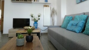 A modern living room with a grey sofa, a wooden coffee table with plants, a flat-screen TV, and a bookshelf. - Condo Entero en Pantano de los Bermejales (Pantano de los Bermejales)