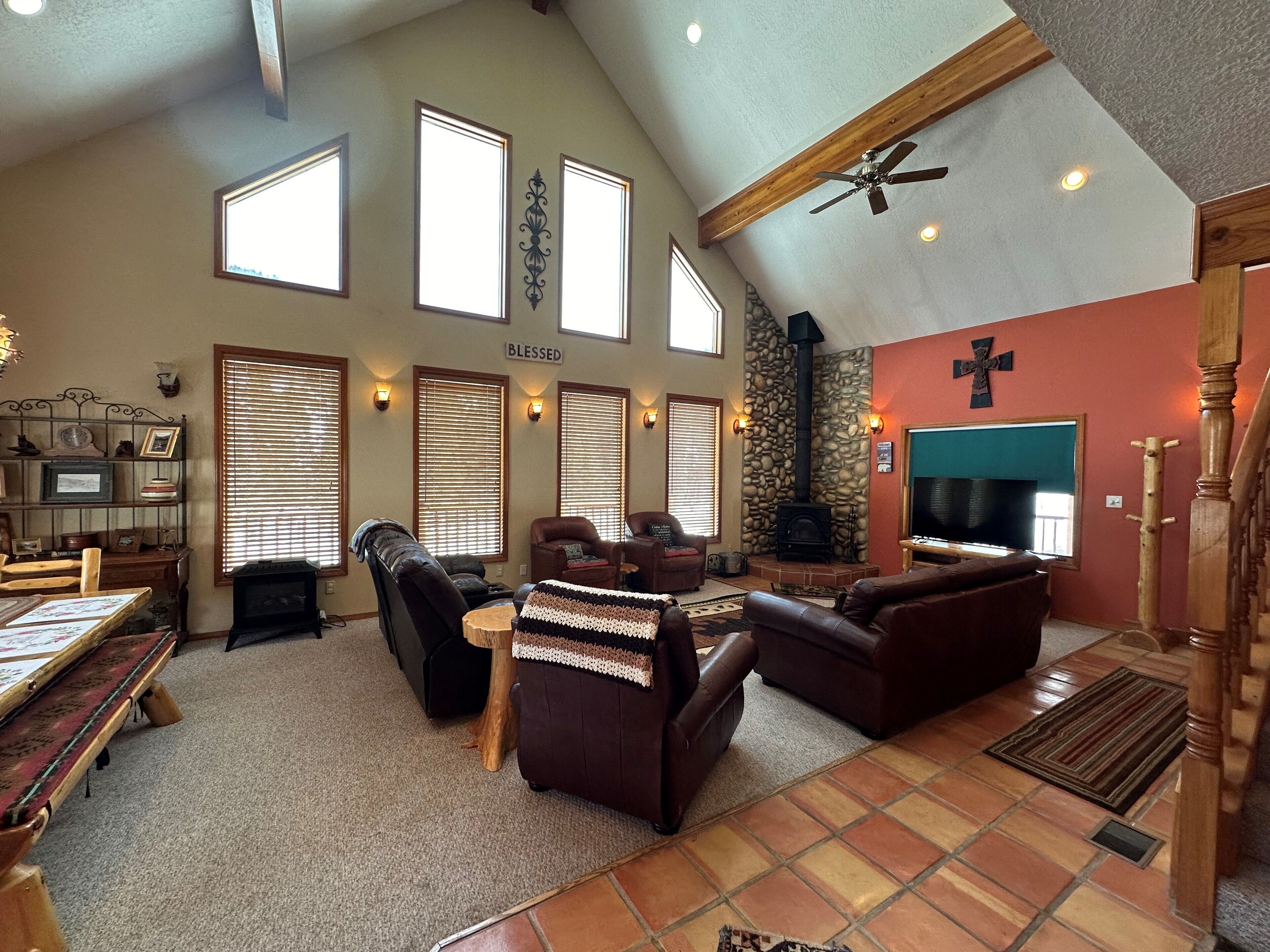 A spacious living room with a stone fireplace, leather sofas, and a television.