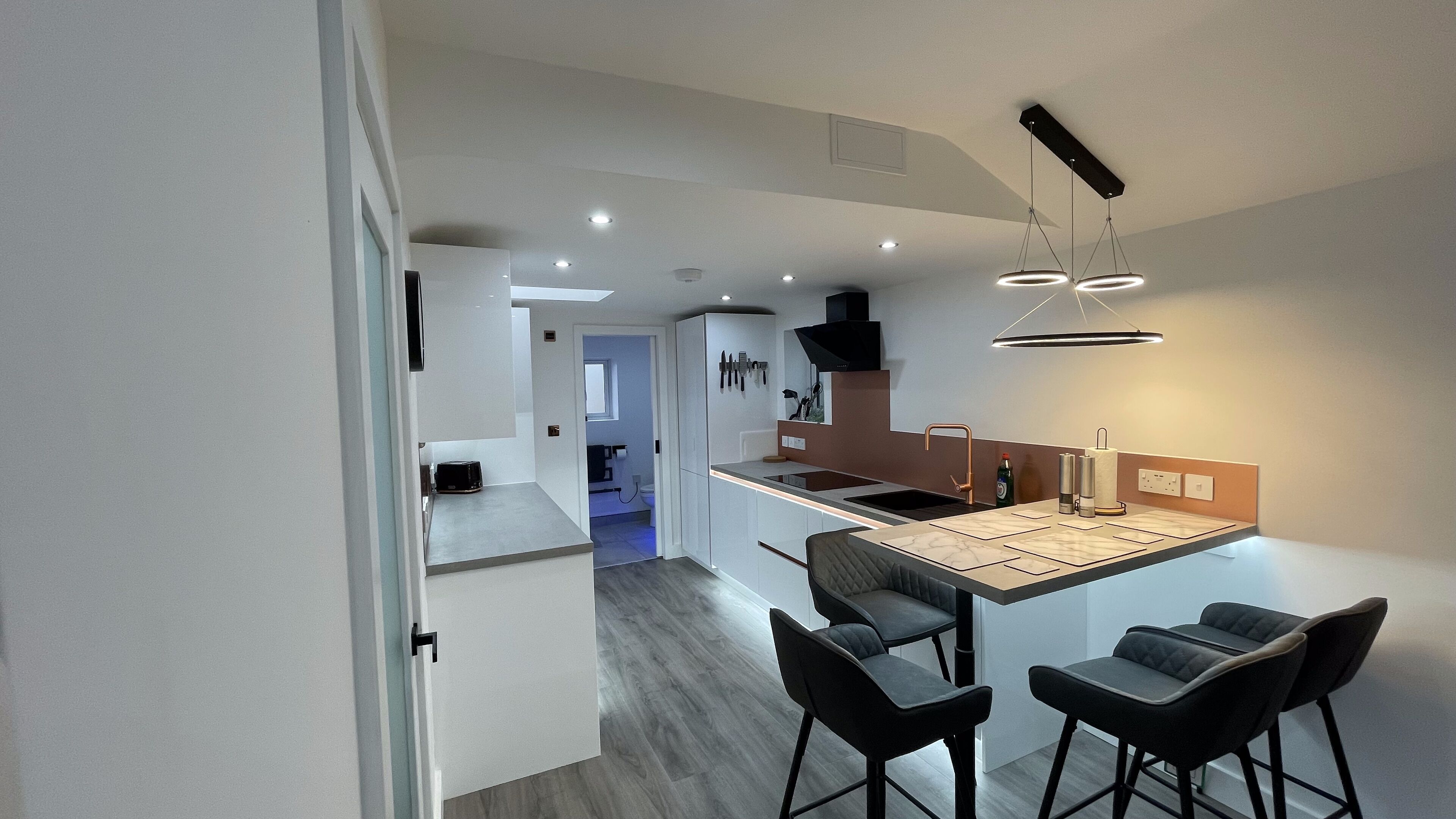 A modern kitchen with a central island, bar stools, and pendant lighting.