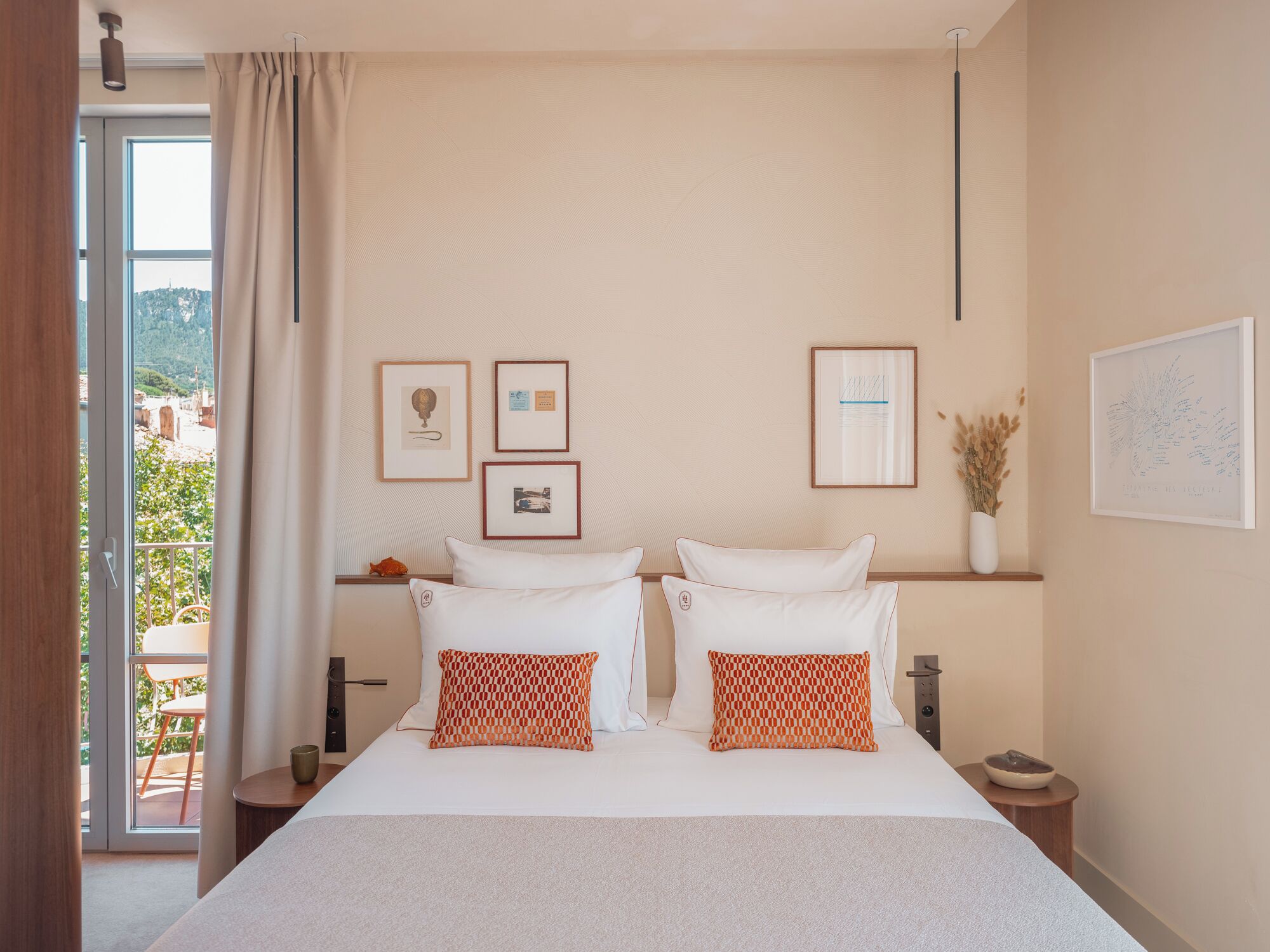 Habitación de hotel con una cama grande, dos almohadas, una mesita de noche y un ventanal con cortinas.