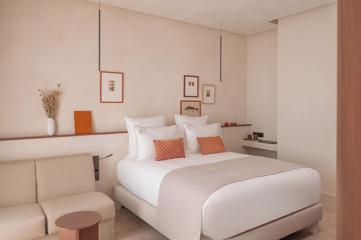 Um quarto moderno com uma cama grande, um sofá, uma mesinha de cabeceira e quadros nas paredes.
