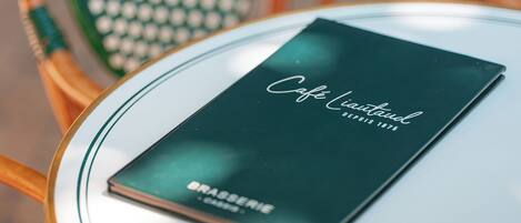 A table with a menu titled "Cafe Land" and a chair with a green and white pattern.