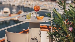 A balcony with a table featuring a drink, a glass of water, and a bowl of snacks. - Hôtel Liautaud Cassis by Germain Collection (Cassis)