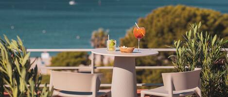 A terrace with a table, chairs, and a view of the sea.