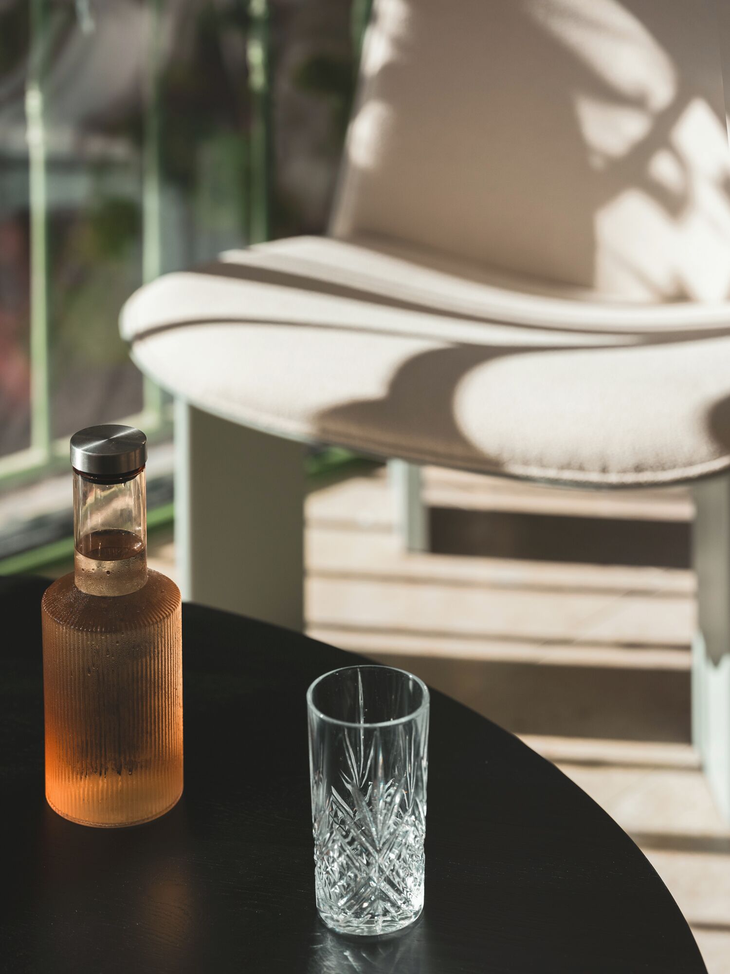 A modern lounge area with a glass table, a bottle, and a glass.