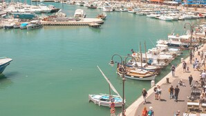 A marina with boats docked, a promenade with people walking, and buildings in the background. - Hôtel Liautaud Cassis by Germain Collection (Cassis)