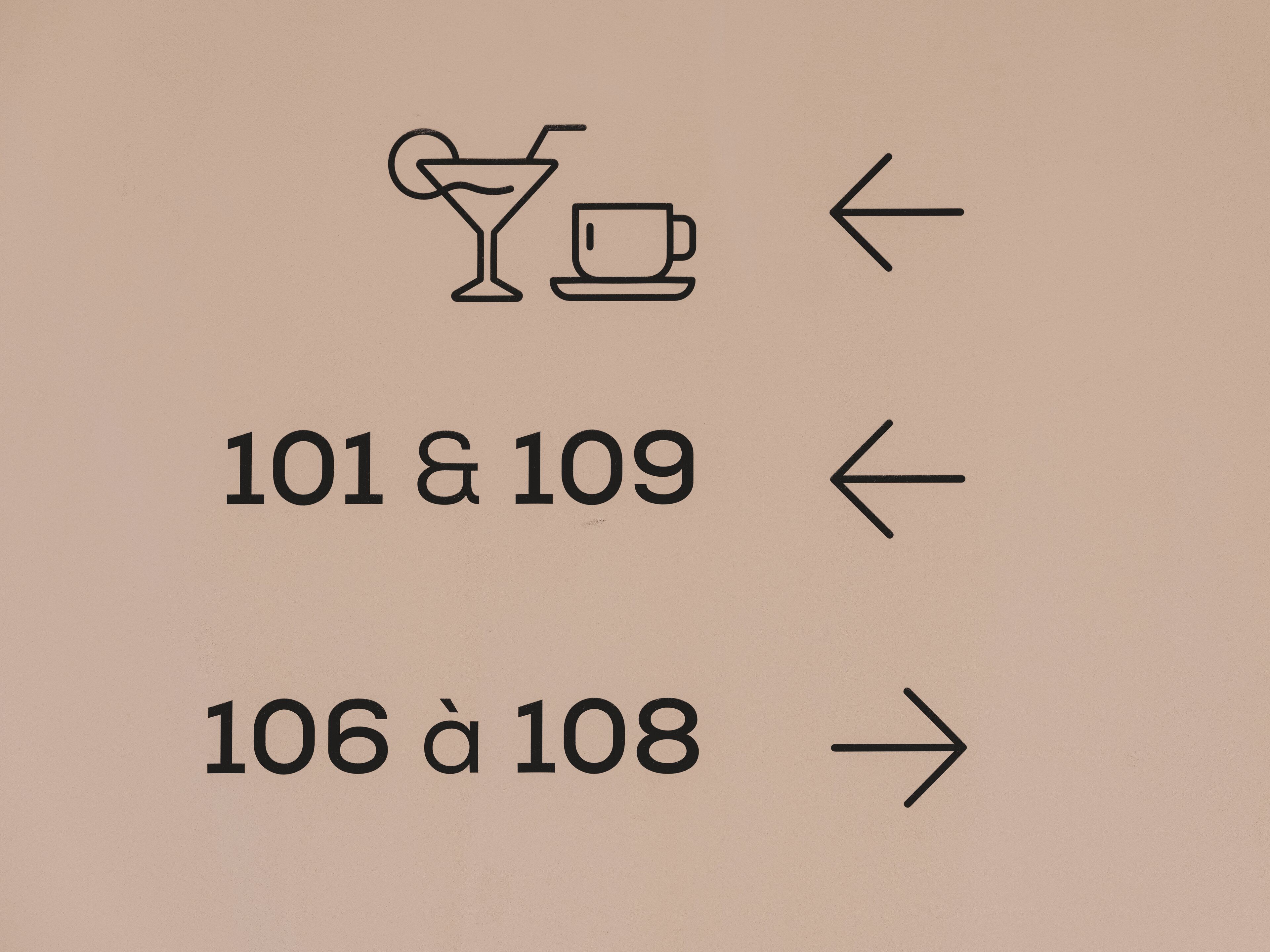 Een routebord met een cocktail icoon en een koffiekop, dat de weg wijst naar kamers 101 & 109 en 106 tot 108.