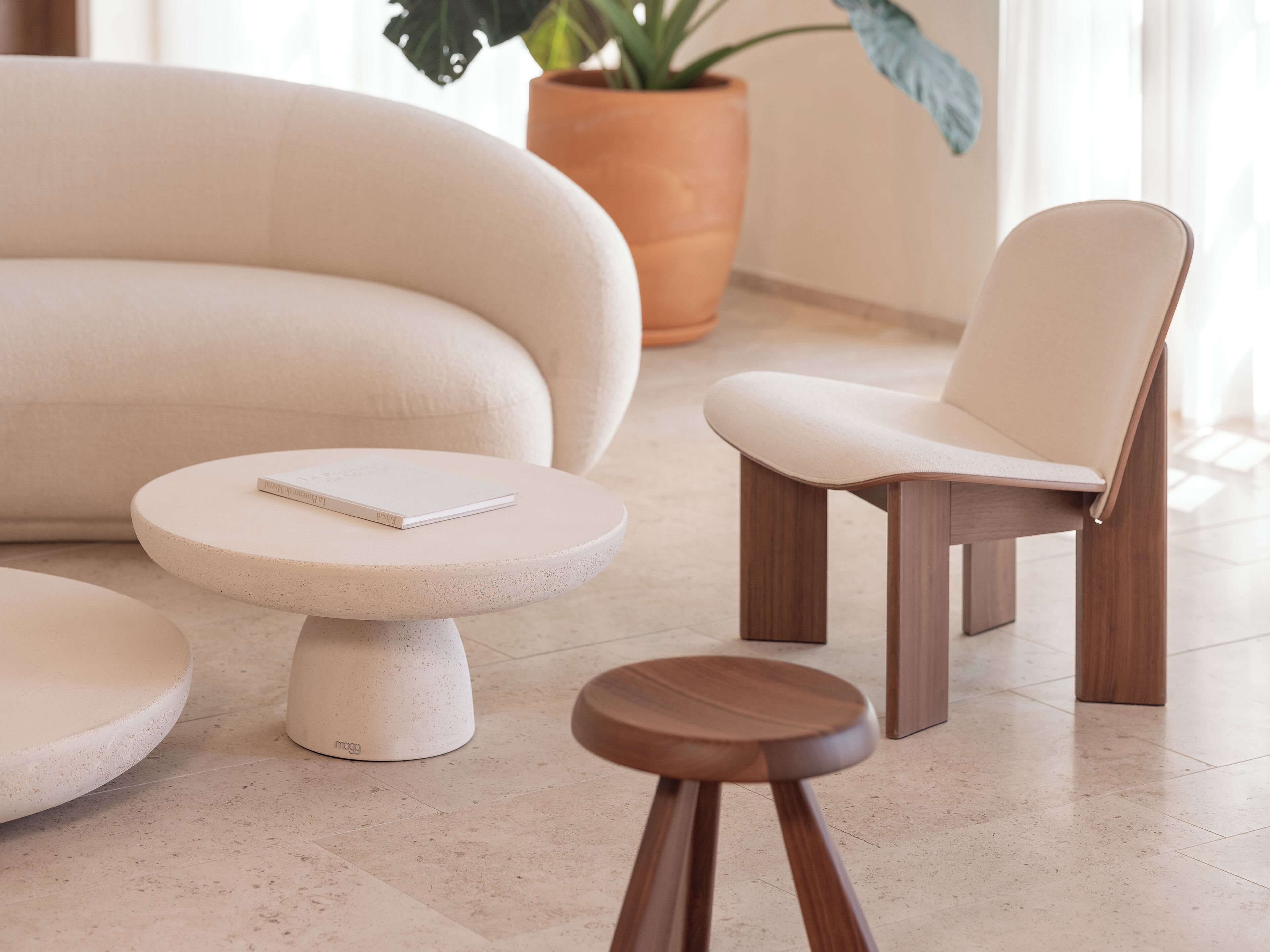 A modern living room with a sofa, a wooden chair, and a small round table with a book.