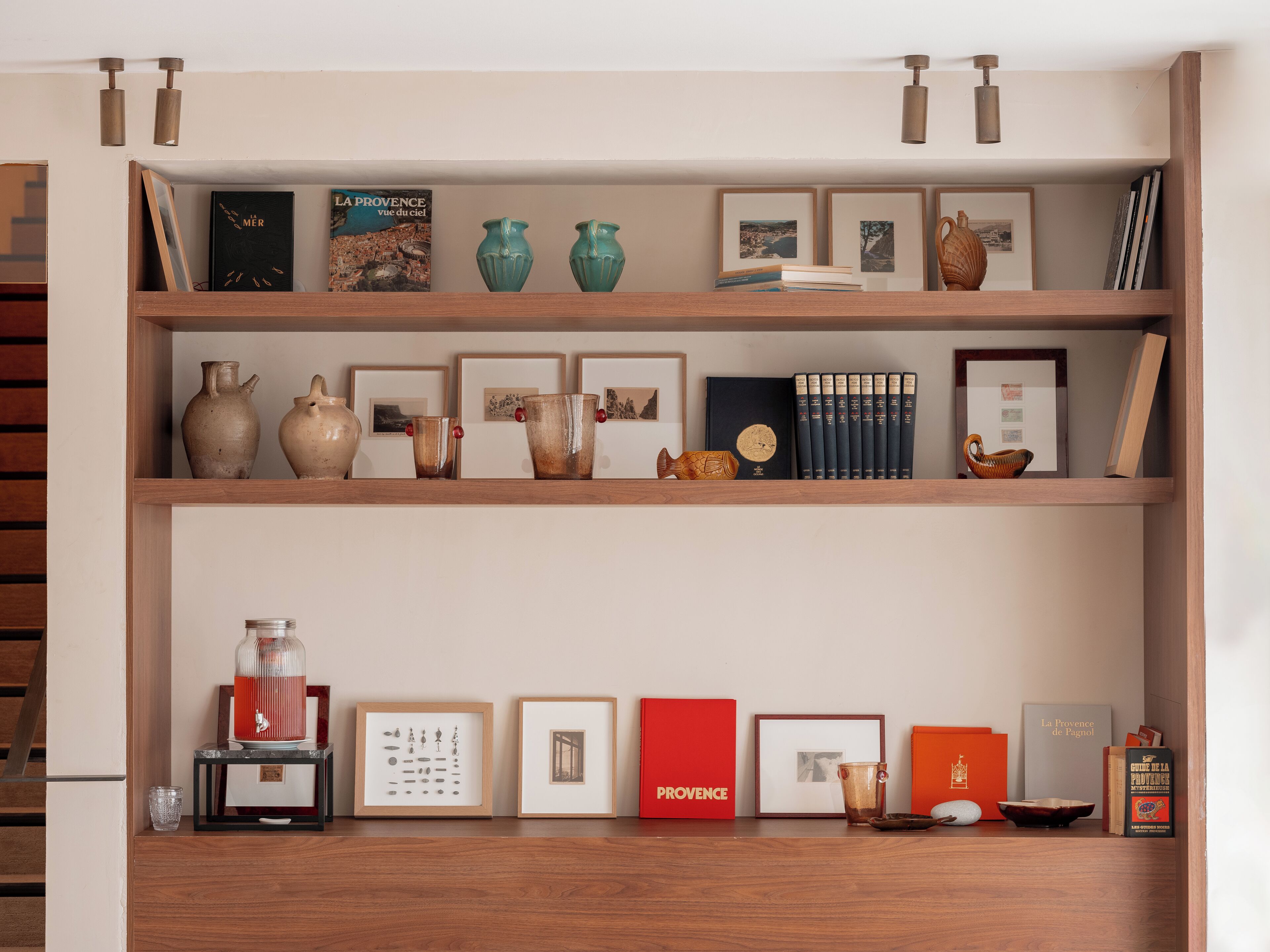 A wooden shelf with various decorative items including books, vases, and framed pictures.