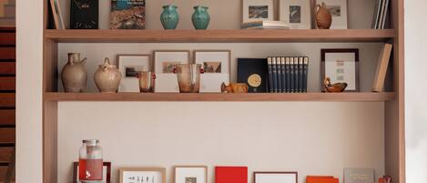 A wooden shelf with various decorative items including books, vases, and framed pictures.