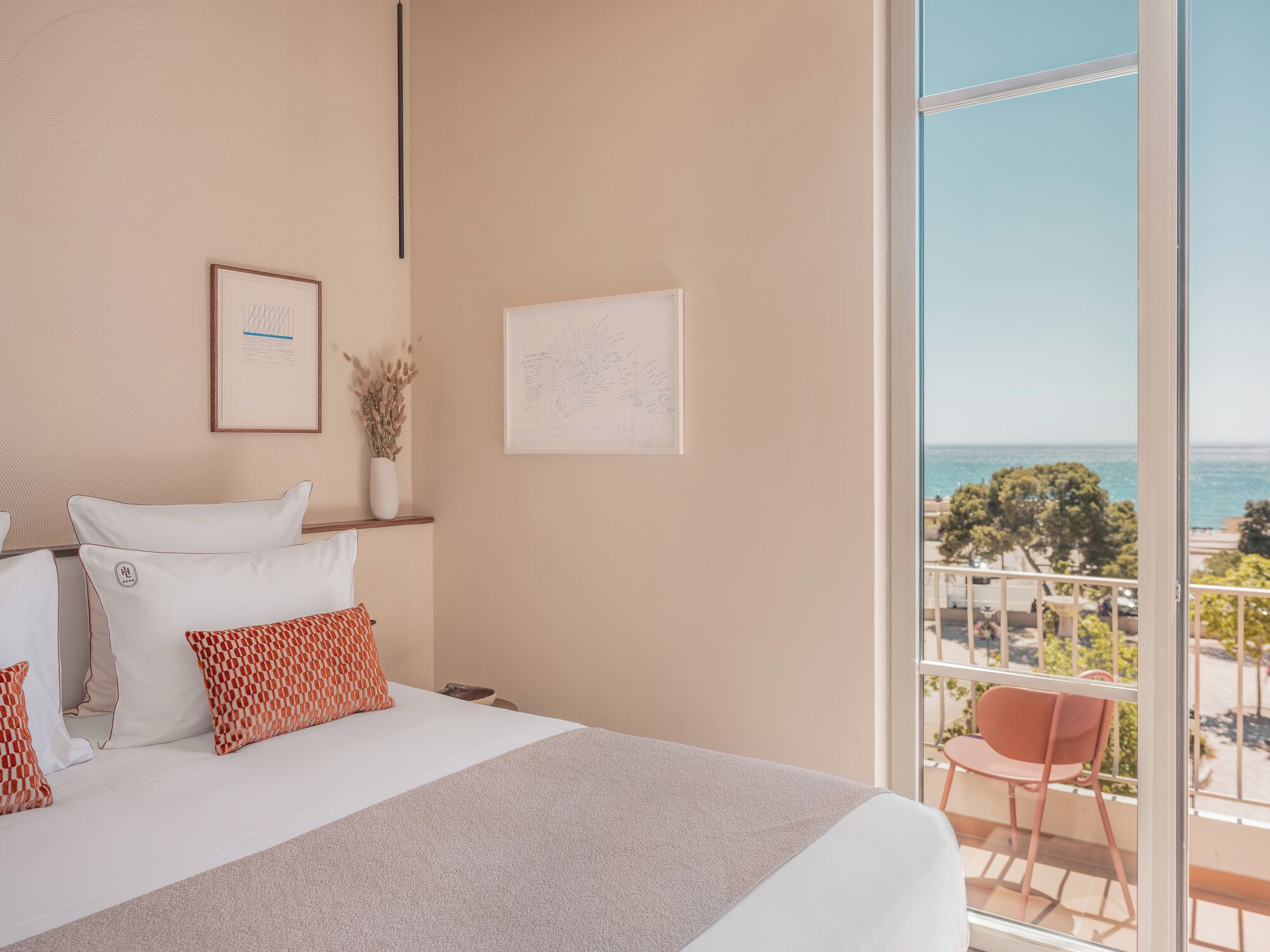 Une chambre avec un grand lit, un balcon donnant sur la mer et une carte encadrée accrochée au mur.