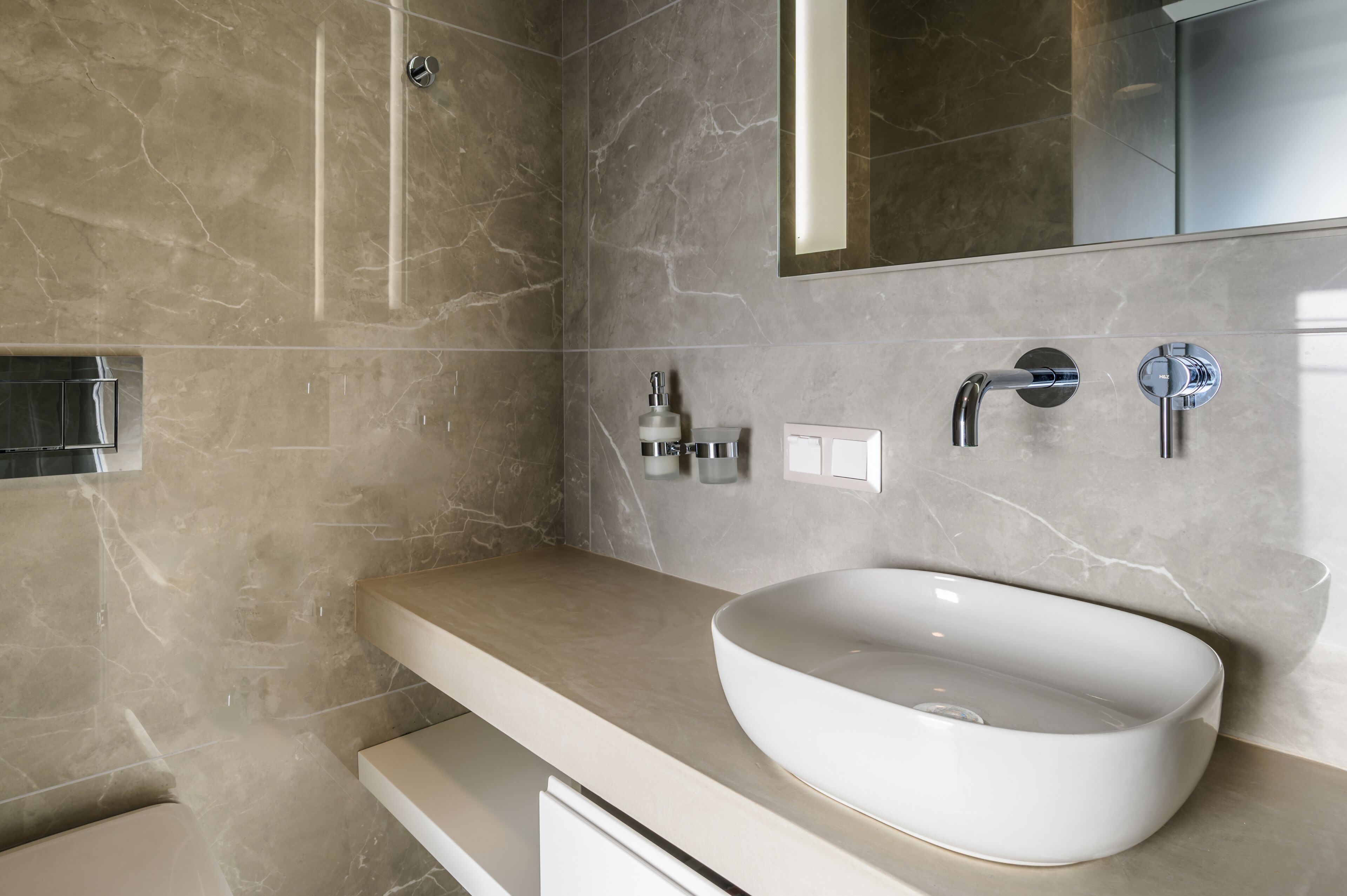 A modern bathroom with a large, oval sink, a mirror, and a shower area.