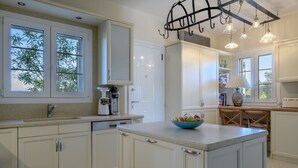 Cocina moderna con armarios blancos, una isla central e iluminación colgante.