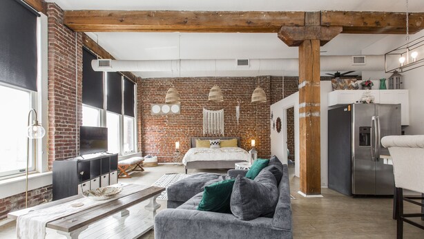 A spacious living area with a sofa, a wooden bench, and a kitchen in the background.